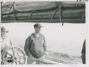 Image of MacMillan standing near wheel on board the Bowdoin